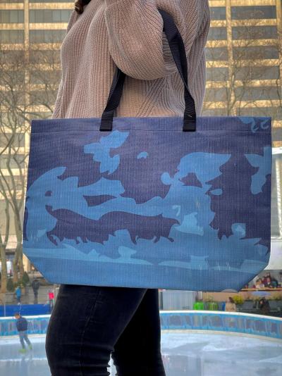 A woman carries a Winter Village barricade tote made from fabric that once covered barricades in Bryant Park New York City.