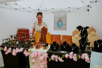 A woman stands behind her booth at the Makers Market in Bryant Park New York City.