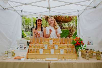 Two women hold up their product at the Bryant Park spring Makers Market in New York City.