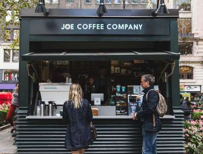 People standing outside at the Joe Coffee kiosk ordering coffee at Bryant Park NYC.