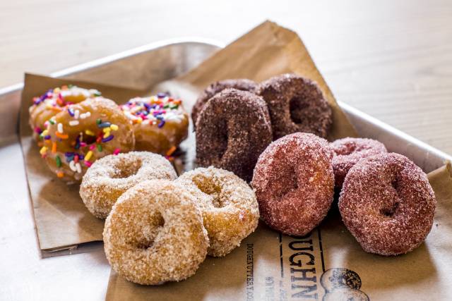 A selection of sugared and sprinkle mini donuts sit on a tray.